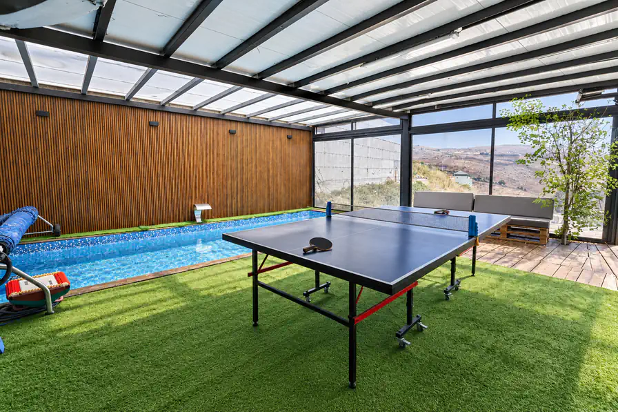 The covered pool with glass walls and a view